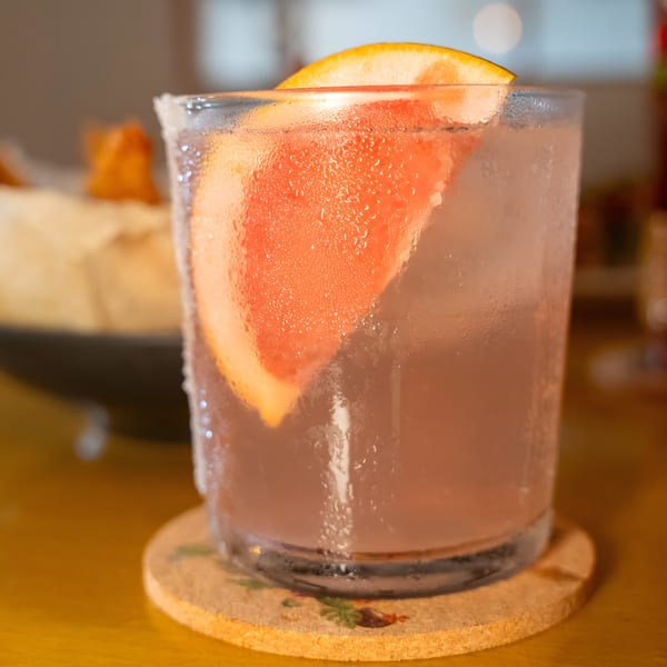A refreshing Shiki Japanese Thai Sushi Bar cocktail with a grapefruit slice, condensation, and a salt rim.