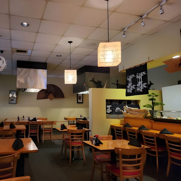 Interior of Shiki Japanese Thai Sushi Bar with wooden tables, chairs, and Japanese-inspired decor.