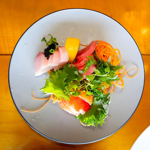 Shiki Japanese Thai Sushi Bar's sashimi platter with tuna, salmon, and yellowtail, garnished with roe and greens.