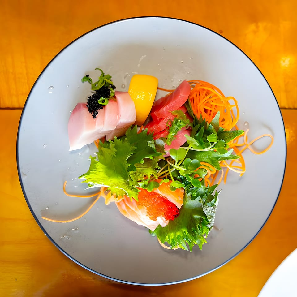 Shiki Japanese Thai Sushi Bar's sashimi platter with tuna, salmon, and yellowtail, garnished with roe and greens.