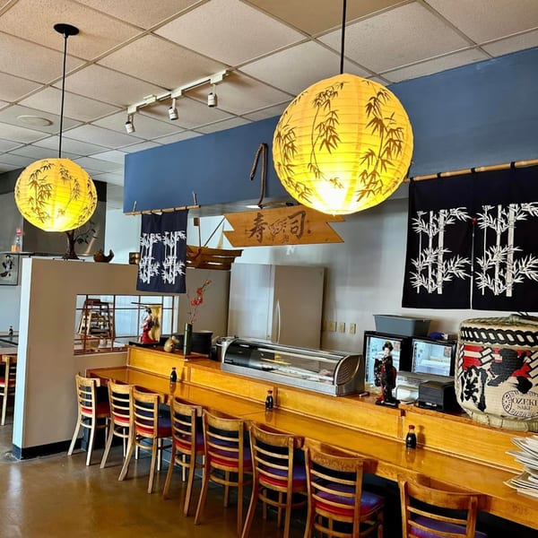 Interior of Shiki Japanese Thai Sushi Bar, featuring a sushi bar with stools and Japanese decor.