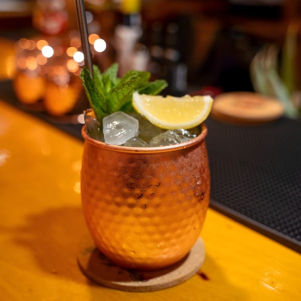 A Moscow Mule cocktail in a hammered copper mug, garnished with mint and a lemon wedge.