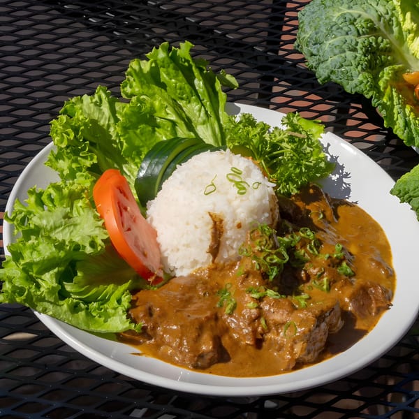 Shiki Japanese Thai Sushi Bar's curry dish with rice, lettuce, tomato, and parsley on a white plate.