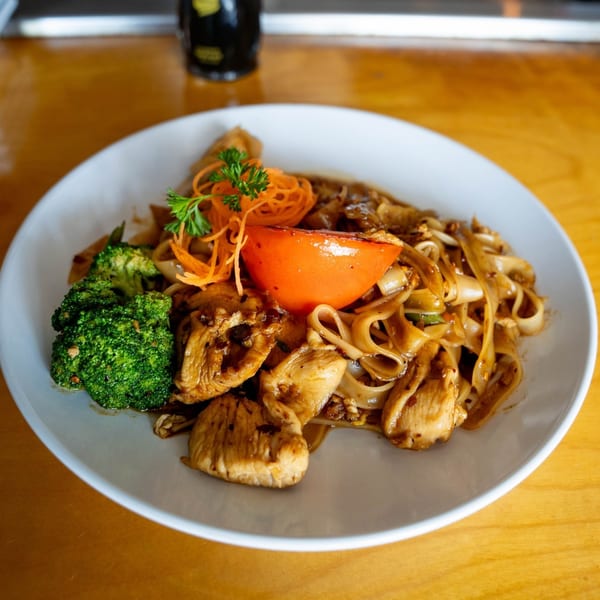 Shiki Japanese Thai Sushi Bar's chicken pad see ew with broccoli, tomato, and carrot garnish.