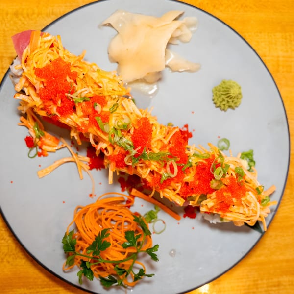 Shiki Japanese Thai Sushi Bar's sushi roll topped with crab, roe, scallions, and served with ginger and wasabi.