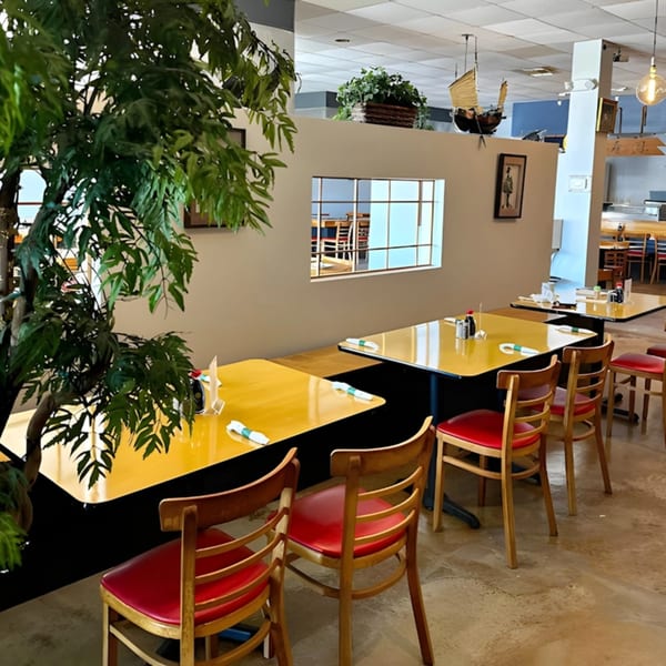 Shiki Japanese Thai Sushi Bar's dining room with yellow tables, red chairs, and a large plant.